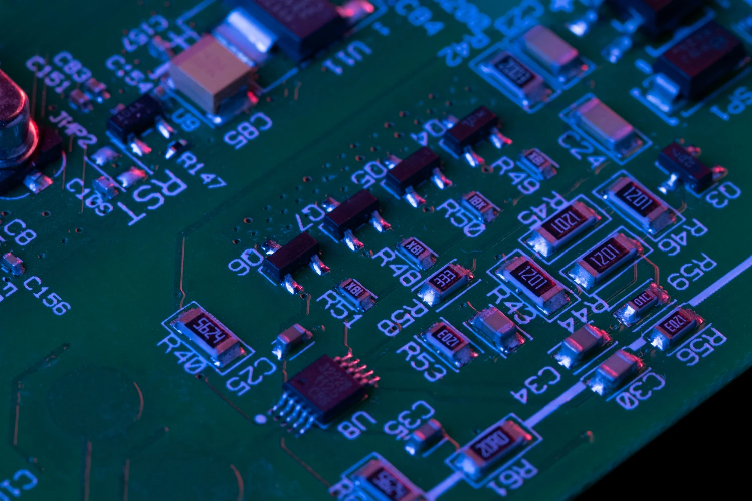 Close-up of a populated circuit board with surface-mount resistors, capacitors, transistors and an IC.